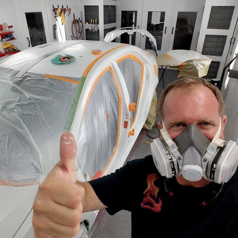 A man with a respirator on in front of an airplane.