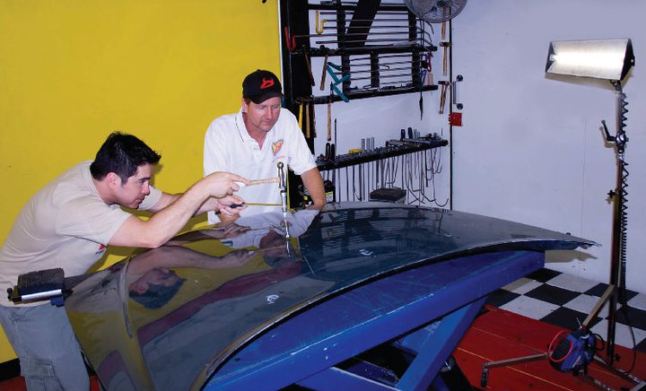 Two men working on a car in a garage.