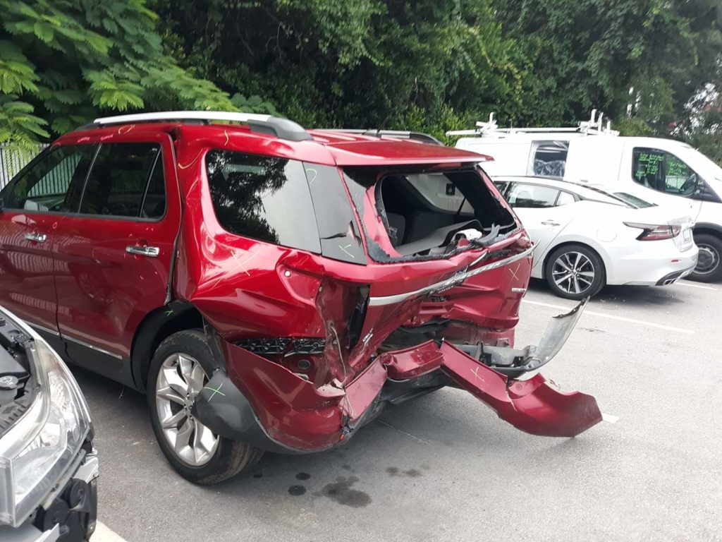 A red suv that has been smashed in the back of it.