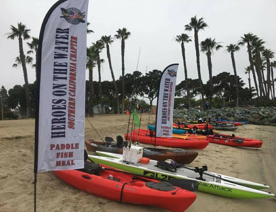 A row of kayaks on the beach with banners.