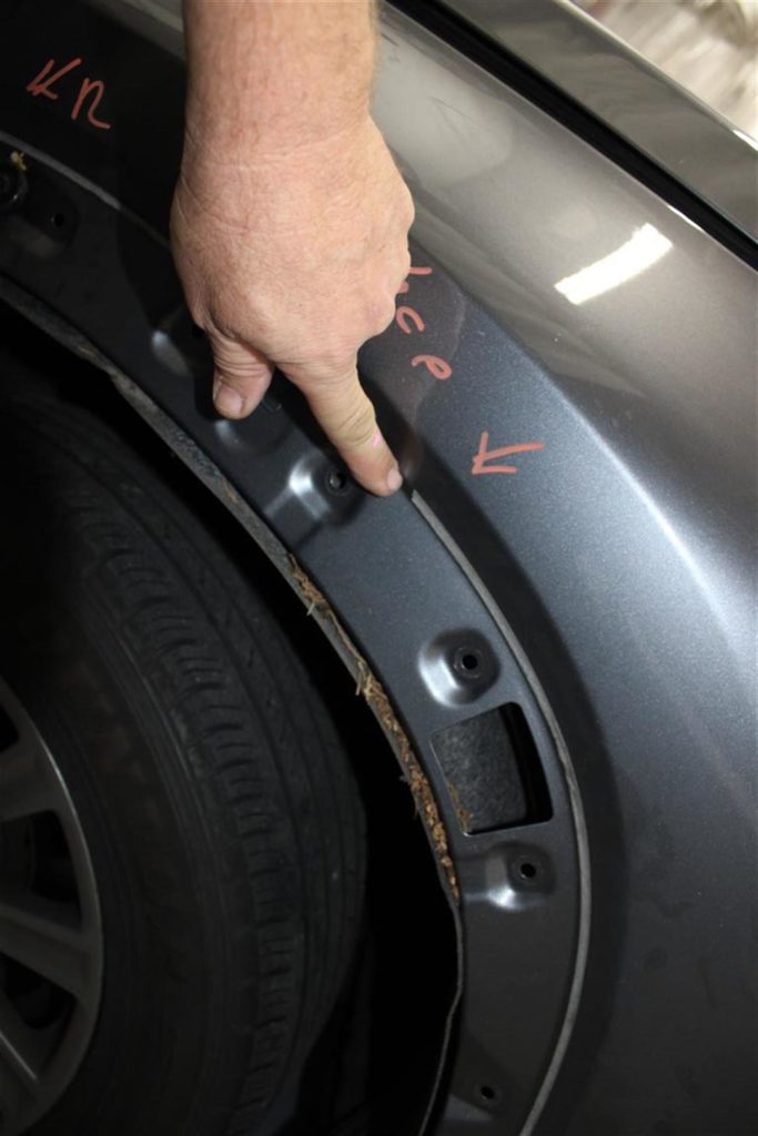 A person touching the tire of an suv.
