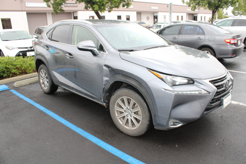 A silver car parked in the parking lot of a building.