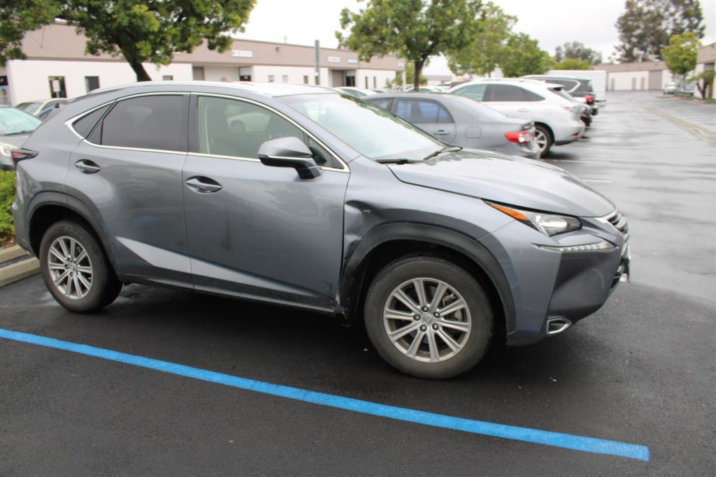 A silver car parked in the parking lot of a building.