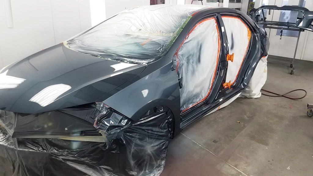 A car that is being painted in the process of being repaired.