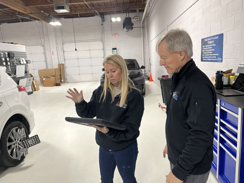 A woman and man in a garage looking at something.