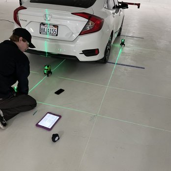 A man is sitting on the ground near a car