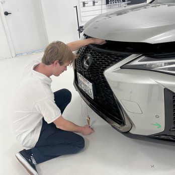 A man is working on the front of a car.