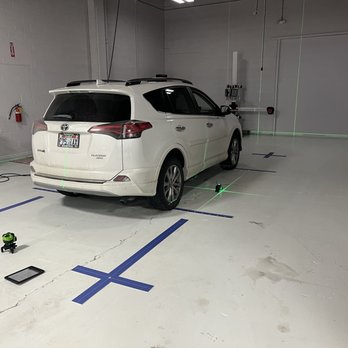 A white car parked in a garage with blue lines on the floor.