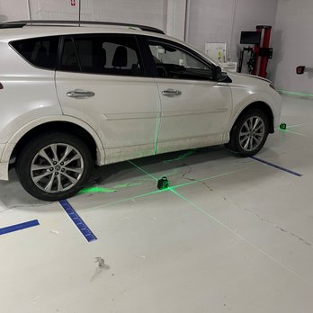 A white car parked in the garage with green lines on it.